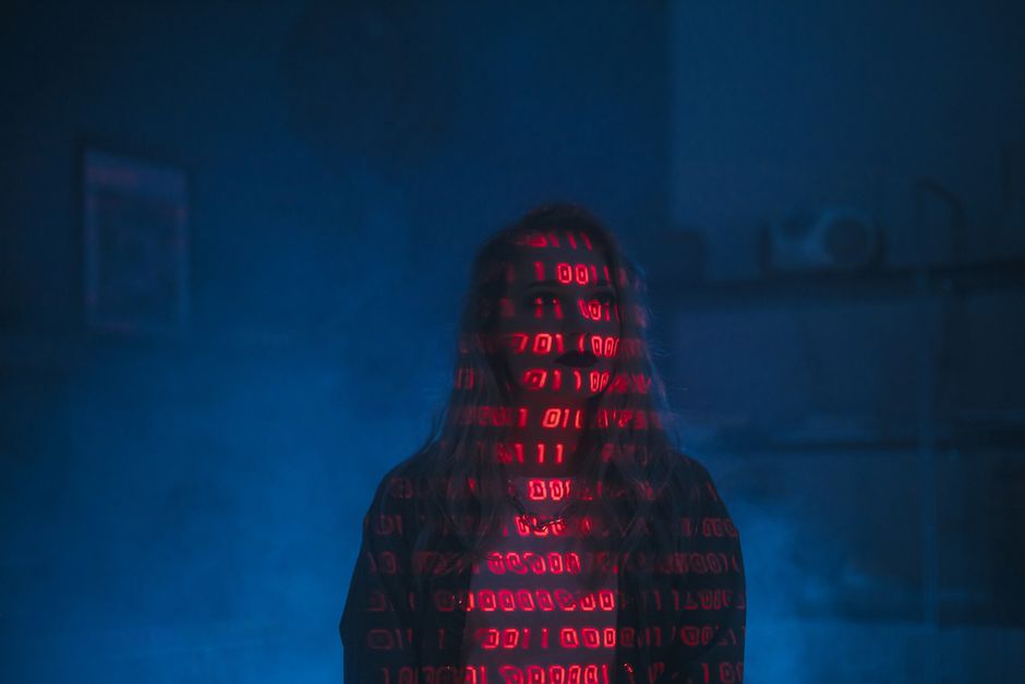 A computer screen displaying lines of programming code with various colors indicating syntax elements. The code appears in a dark-themed text editor, with the lines slightly blurred and illuminated by